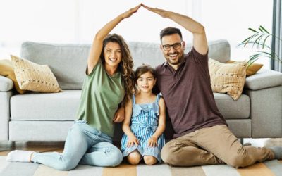 Portrait of a young family forming roof with their hands at new home
